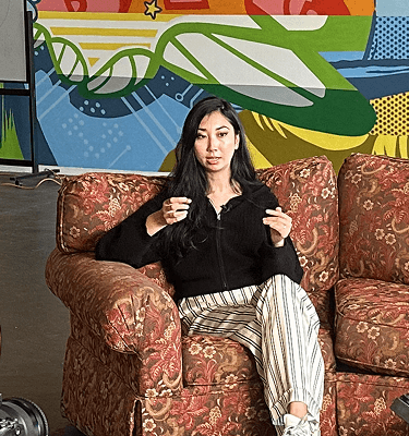 Podcast interview set: subject on left couch, host on right couch, camera and microphone in foreground